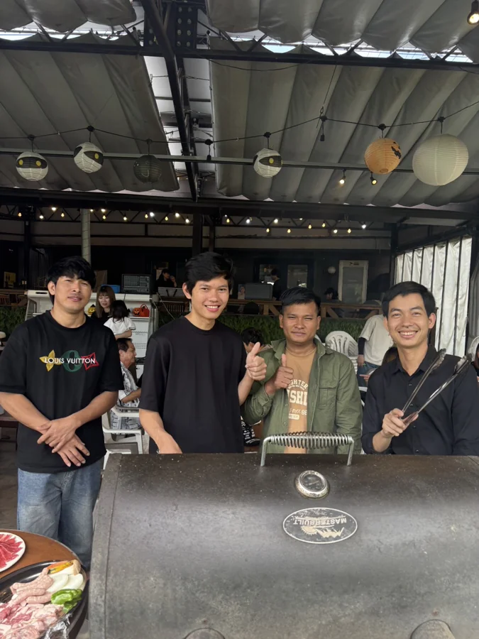 BBQのグリルを囲み、笑顔を見せる4人の仲間